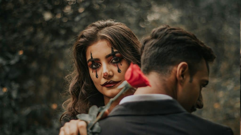 A woman with a makeover holding a red rose while standing next to a man.