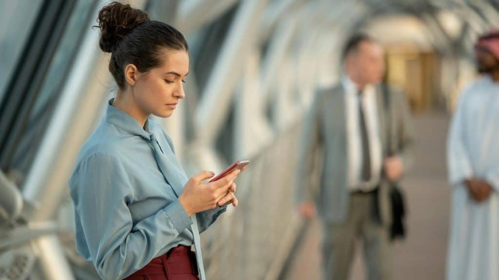A woman standing in a walkway looking at her phone.