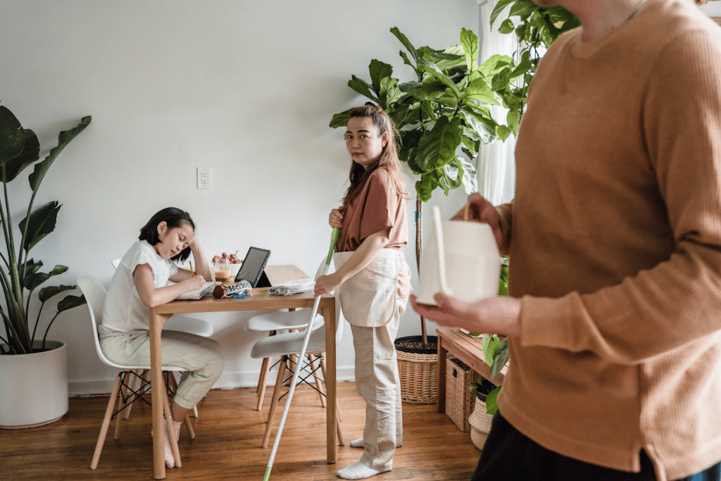 A Woman Holding a Mop Looking at the Person Wearing Brown Sweater