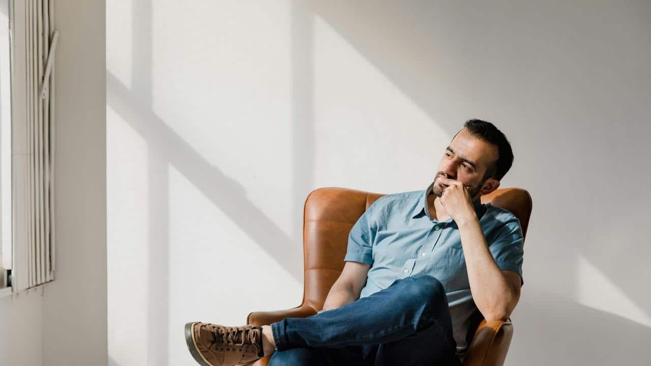 A man sitting in a chair and looking thoughtfully to the side