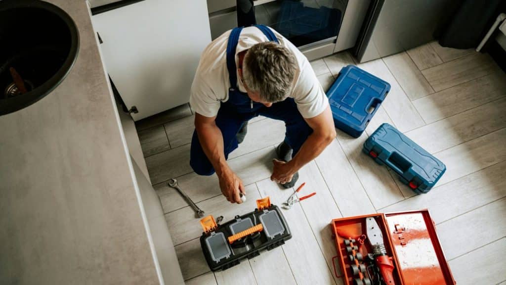 Overhead view of a male plumber working on the floor with toolboxes.