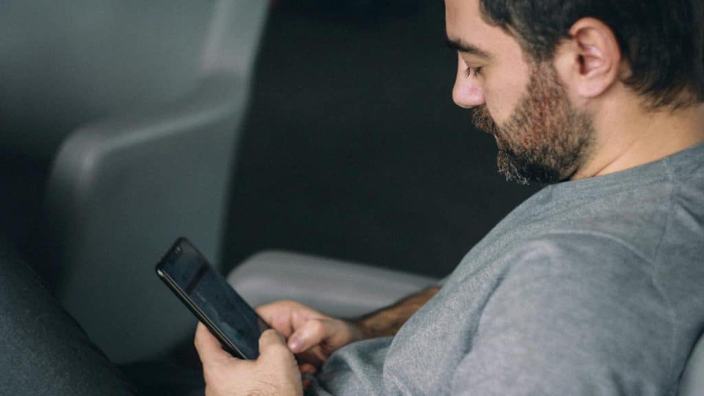 A man sitting on a couch looking at his smartphone.