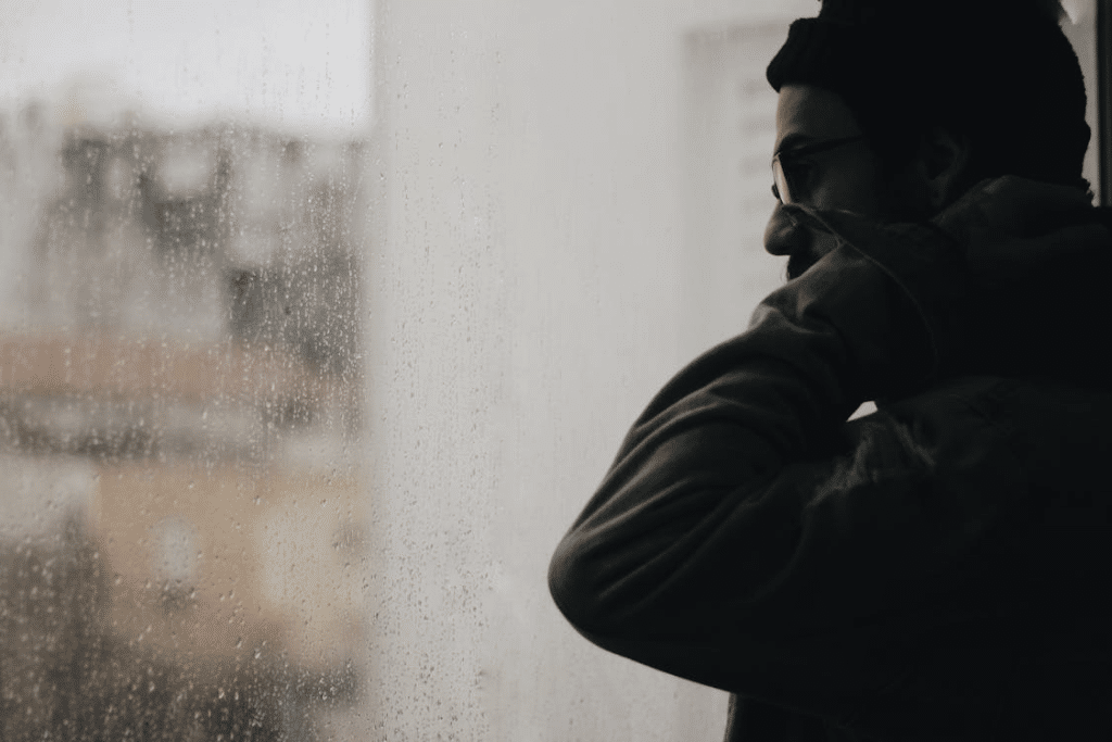 Man Standing Beside a Wet Window