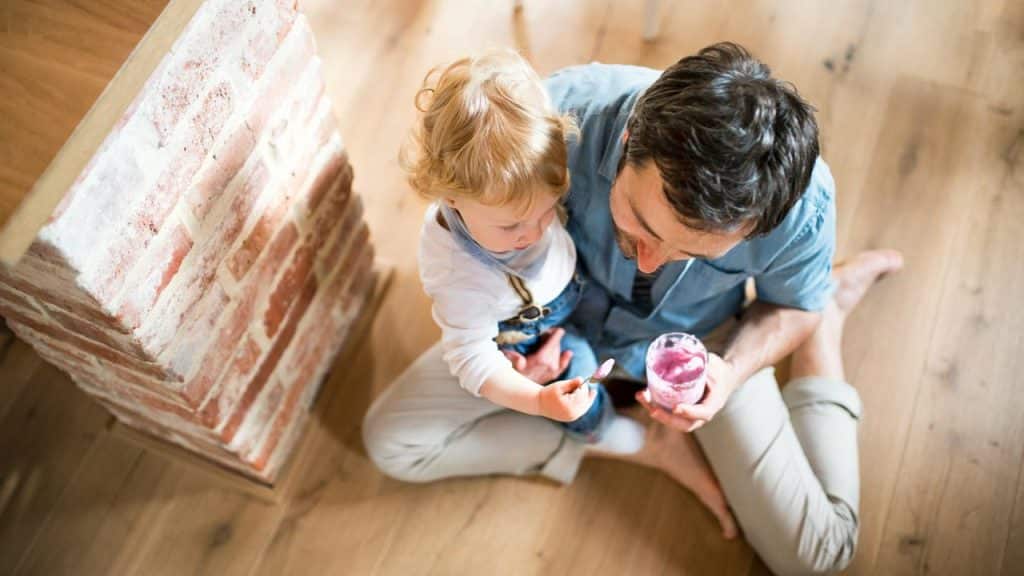 A father feeding his child with a smoothie.