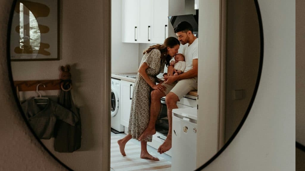 A mirror image of a couple holding and kissing their newborn.