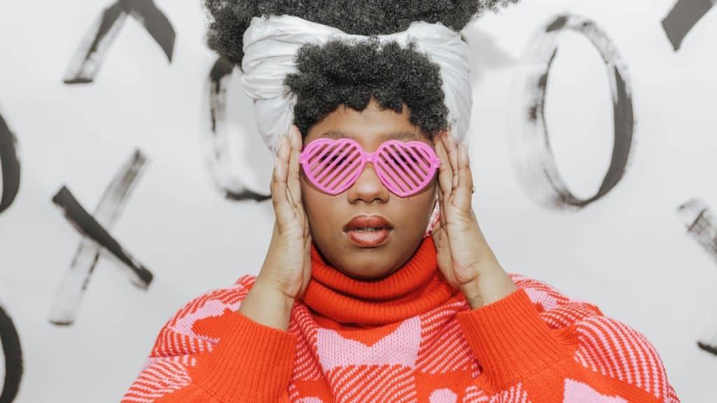 A woman with pink heart-shaped sunglasses covering her eyes.