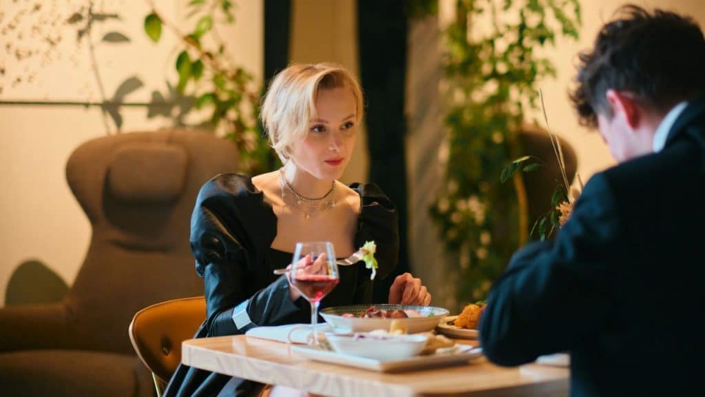 A blonde woman eats dinner with a man across a table in a restaurant.