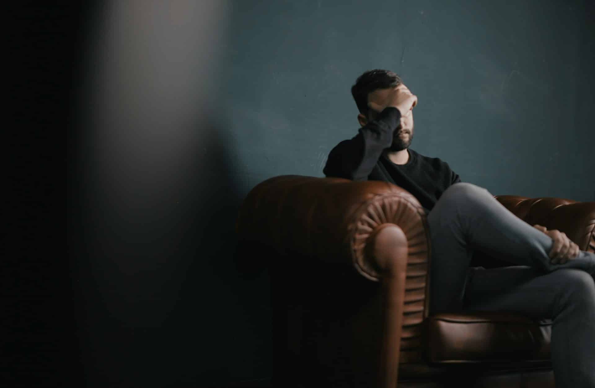 A tired man sitting in a couch.