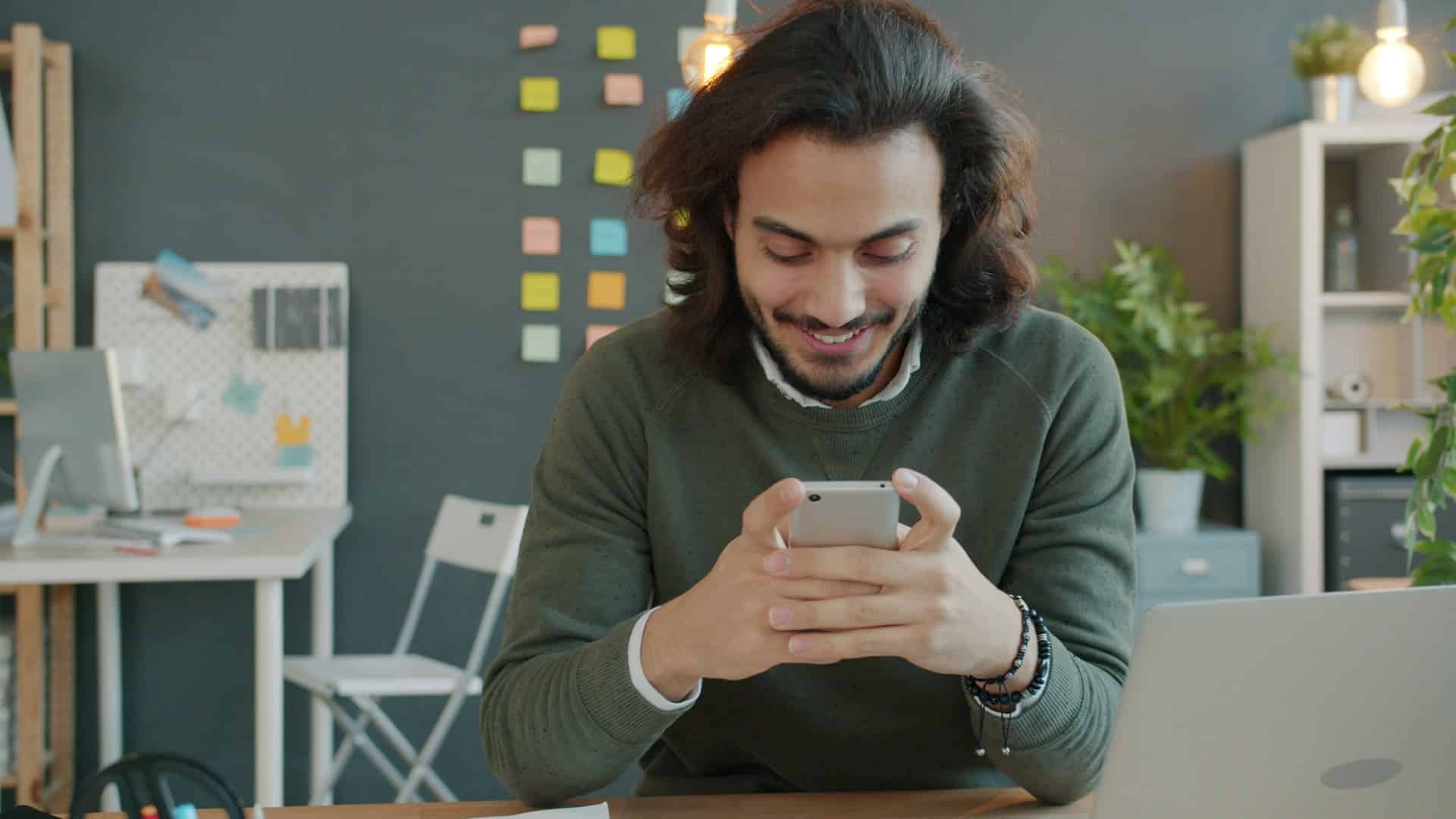 A man smiling while looking at his phone.