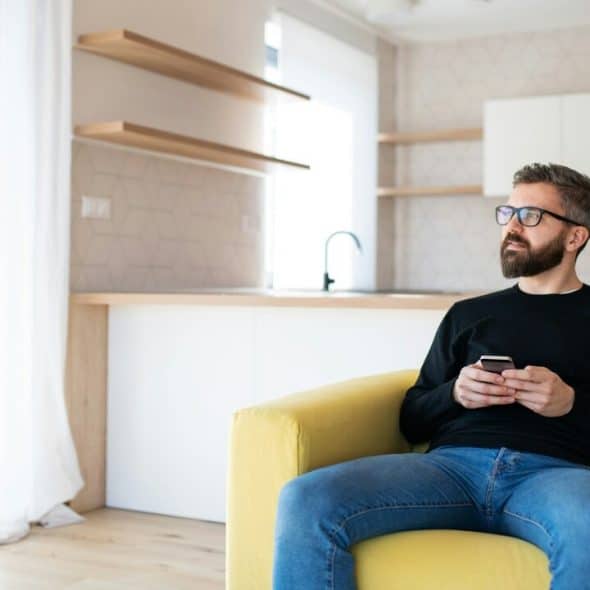 A man sitting on sofa holding his phone