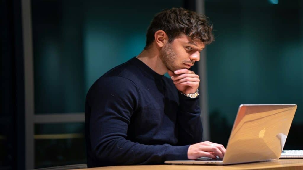 A man in front of his laptop thinking