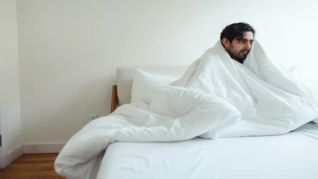 A man wrapped in a blanket looking sad