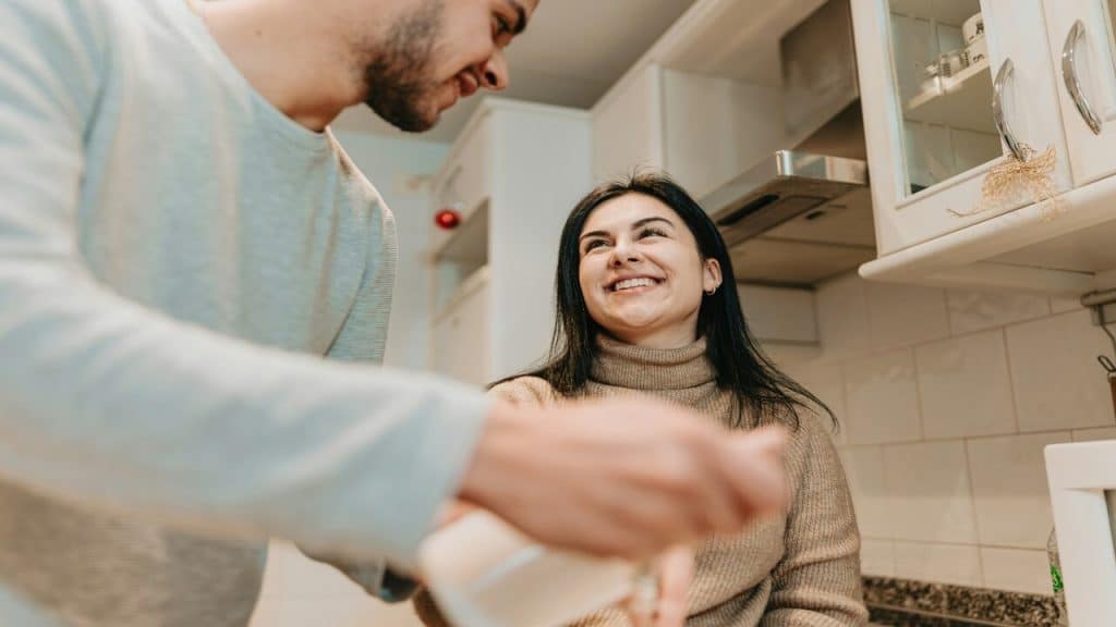A couple smiling at each other in the kitchen