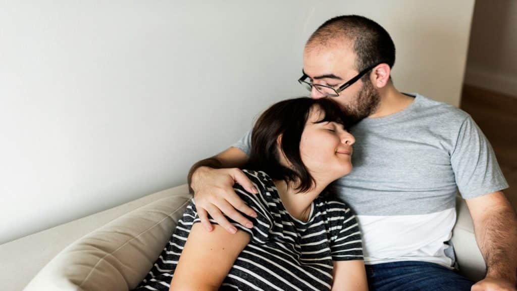A man kissing his wife’s head