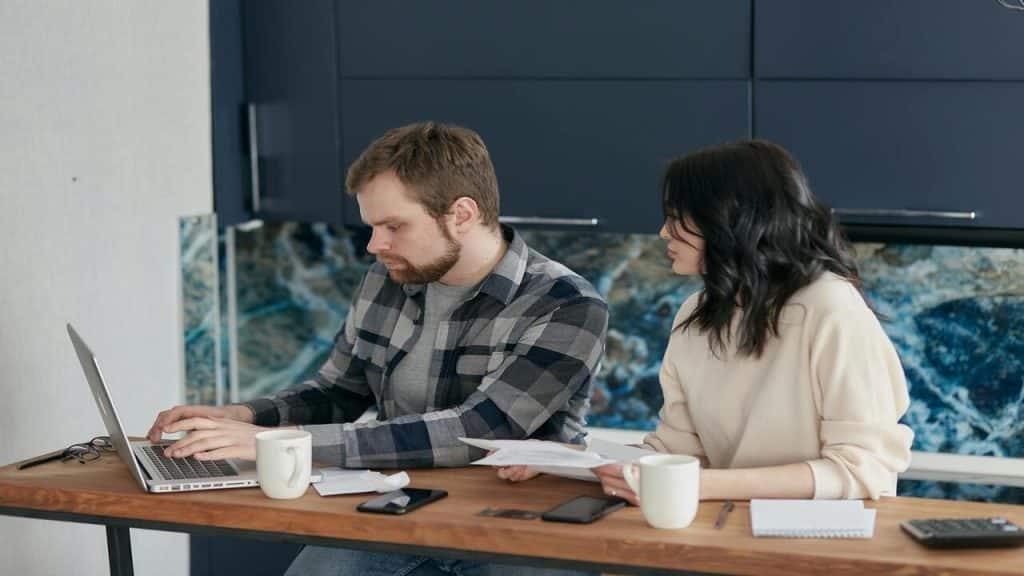 A man and woman looking sad with laptop and documents