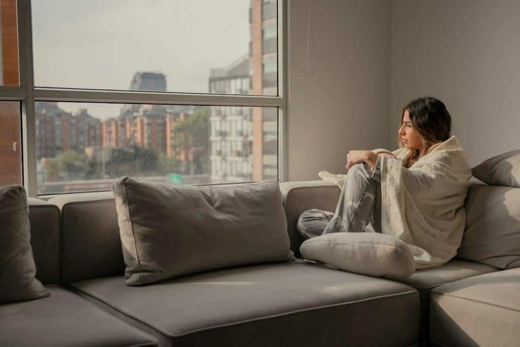 A woman sitting on a couch and looking out the window.
