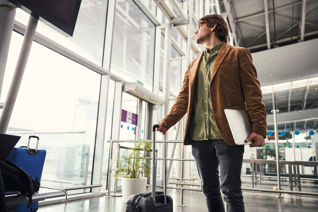 A man looking out the window waiting for a flight.