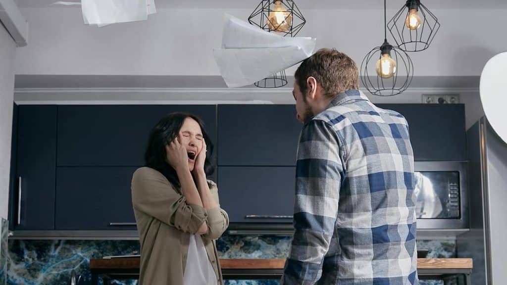 White man yelling at a distraught woman in a modern kitchen.