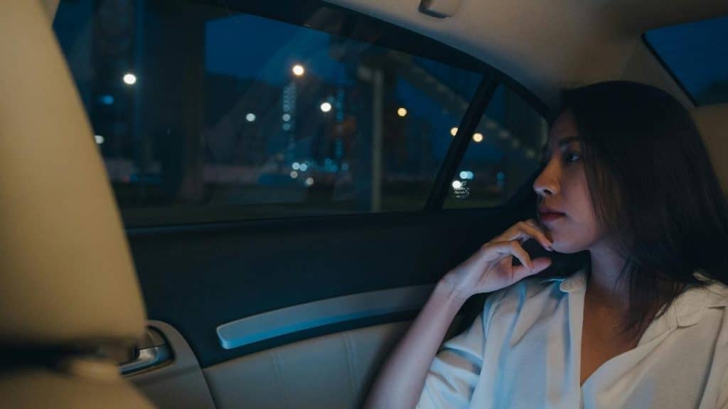 A person sits in a car at night, gazing out the window.