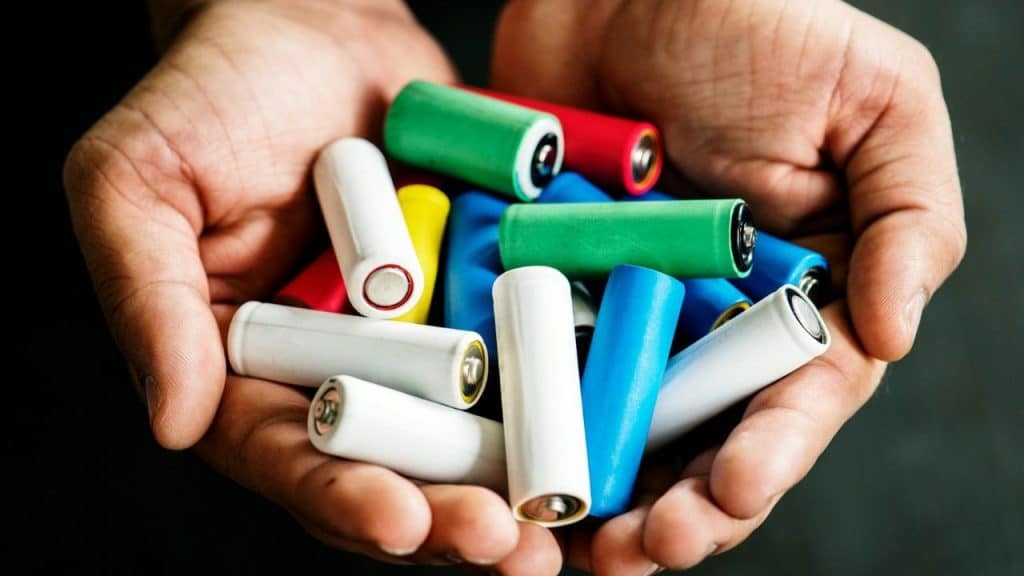 A pair of hands cupping a variety of brightly colored AA and AAA batteries.