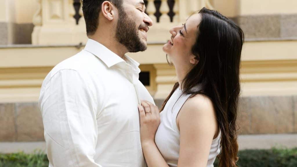 A couple smiling and leaning toward each other in an affectionate pose.