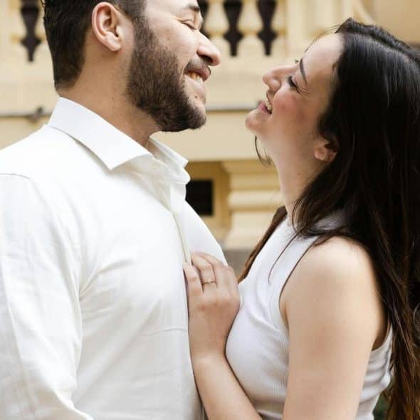 A couple smiling and leaning toward each other in an affectionate pose.
