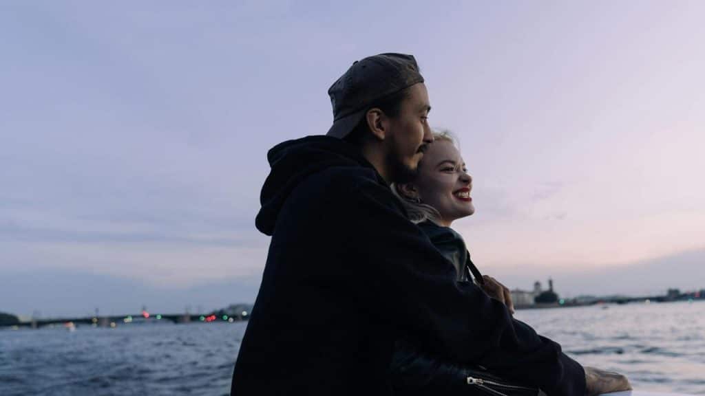 A couple embracing by the water at dusk.