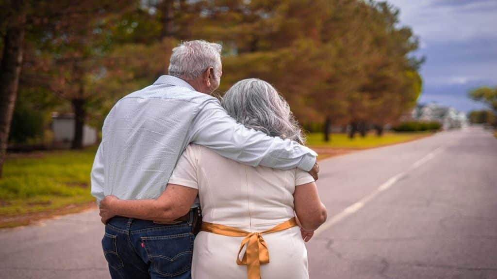 An older couple walking with their arms around each other