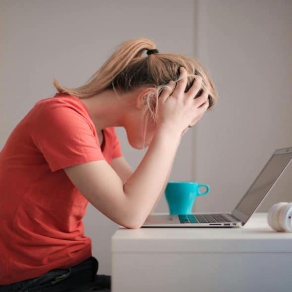 A woman looking stressed in front of her laptop