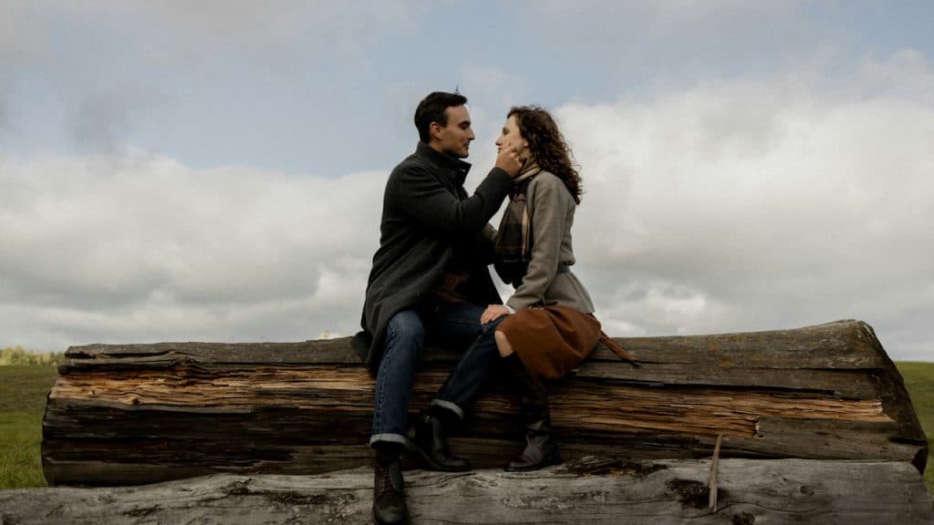 A man and a woman sitting on a log.
