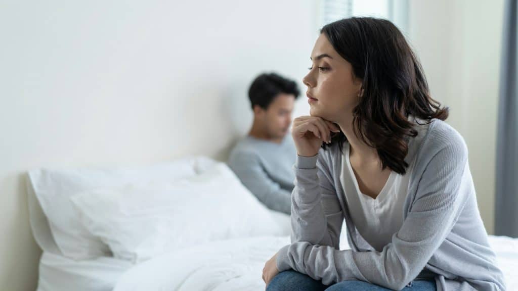 Woman looking away from man after an argument on the bed.