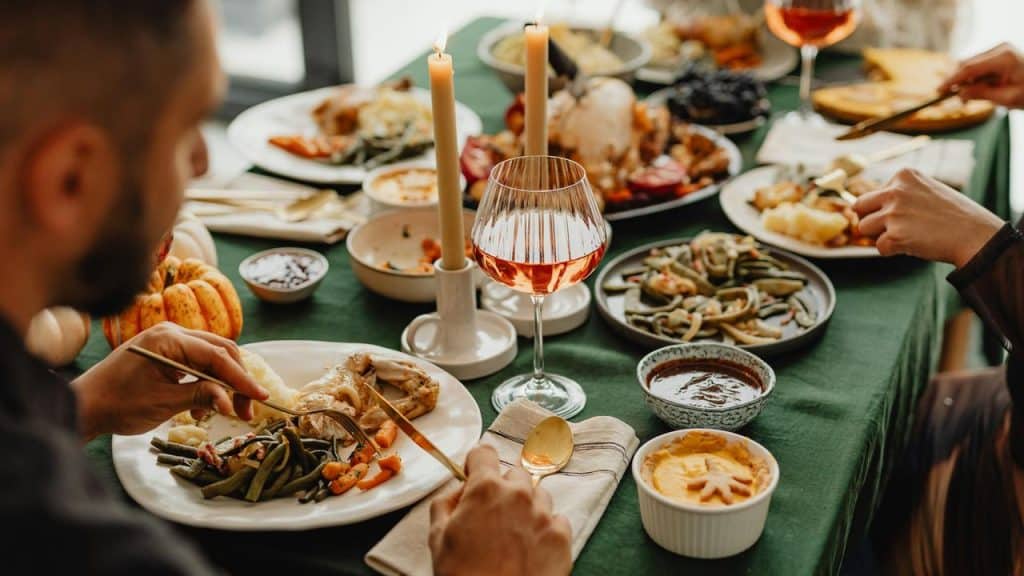 A festive dinner table set with food, wine, and candles.