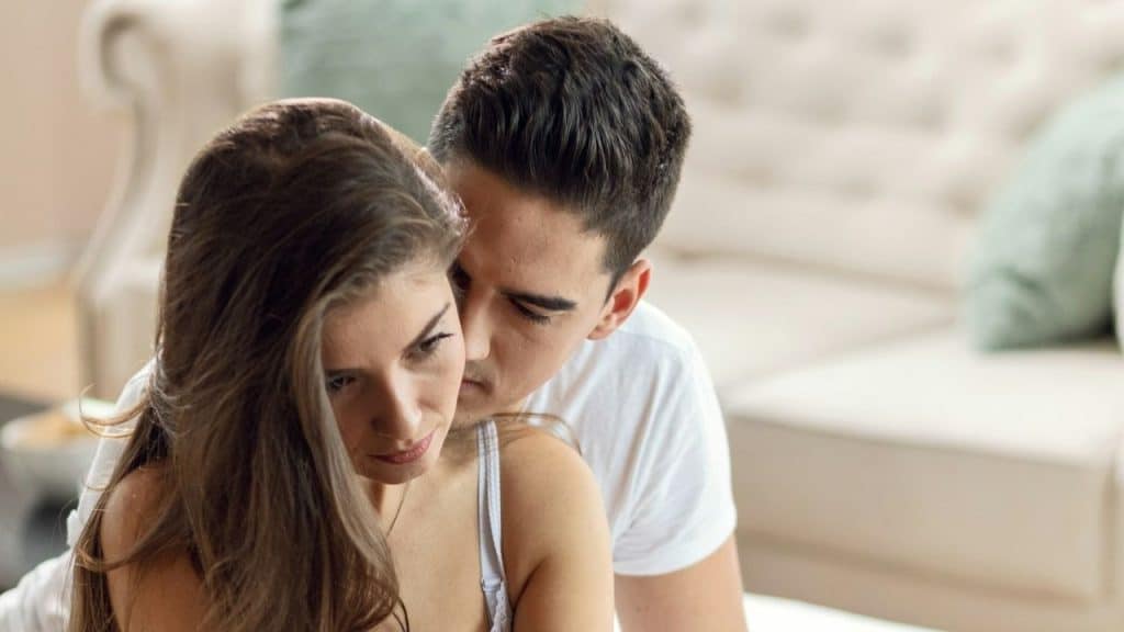 Man in white shirt leaning close to a woman with long brown hair in a living room.