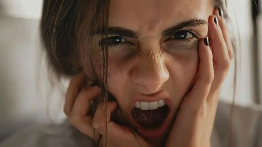 Woman's face in an extreme close-up, yelling or screaming with a distressed expression.