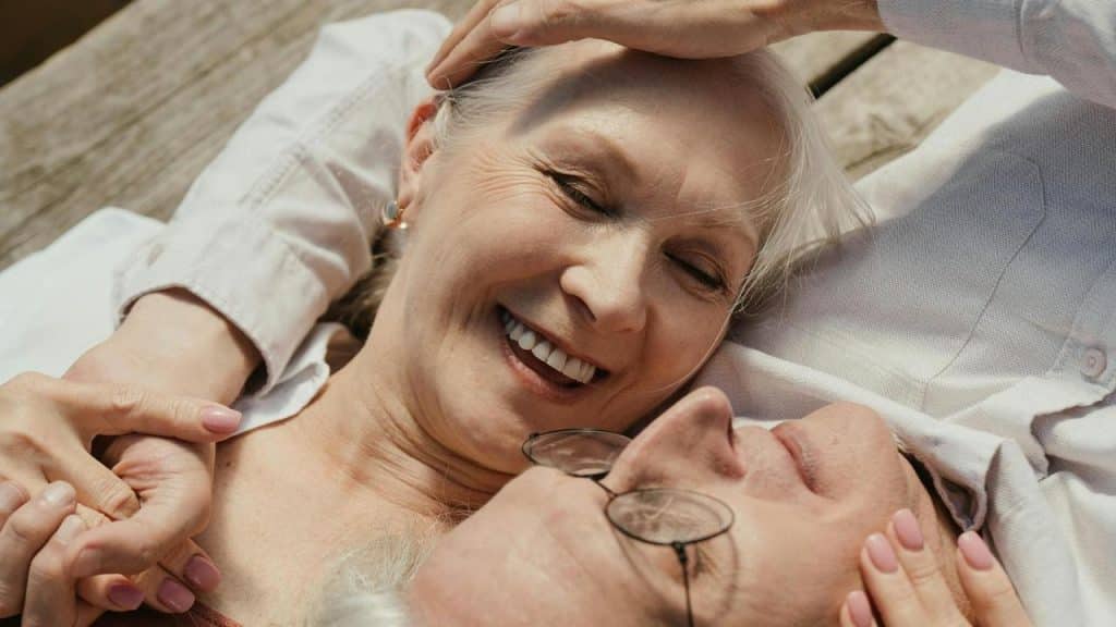 An older couple lying close together and smiling warmly.