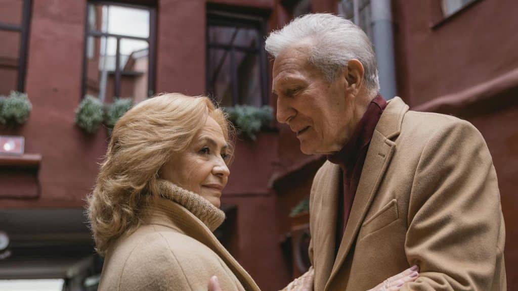 An older couple standing close together and sharing a warm moment outdoors.
