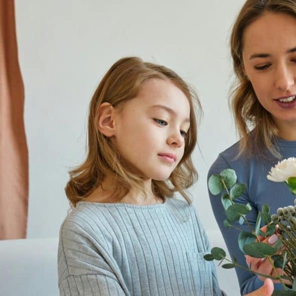 A woman and a young girl arranging flowers together indoors.