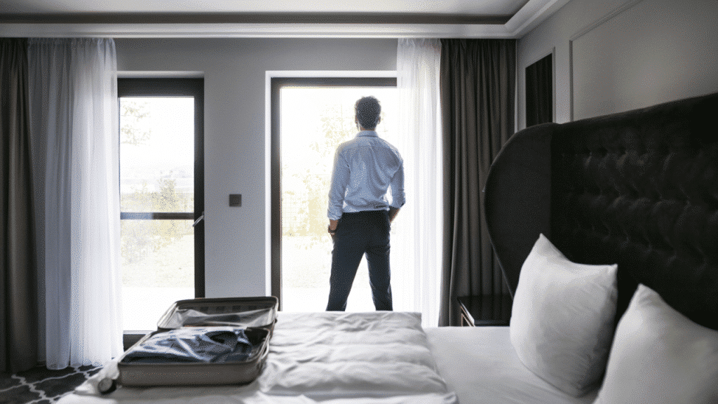A man looking out the window of a hotel