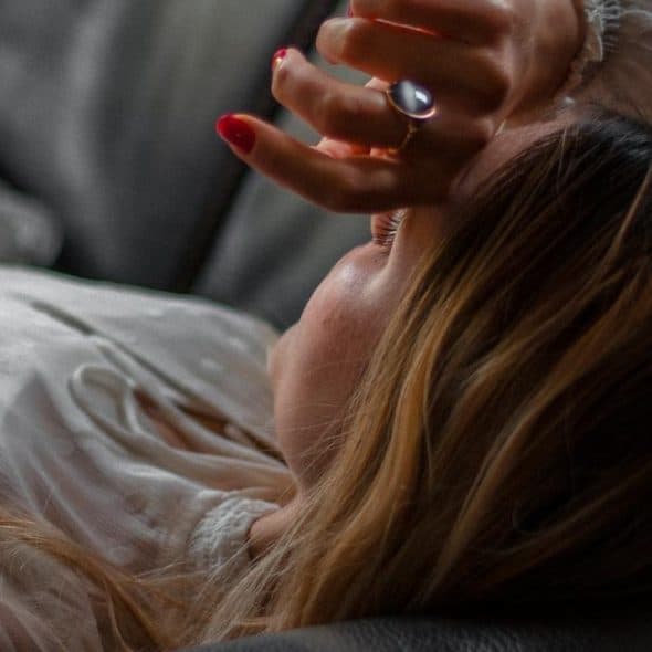 A woman lying on a couch with her hand over her face.