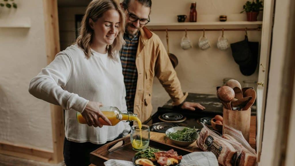 A couple preparing food and pouring juice together in a cozy kitchen.
