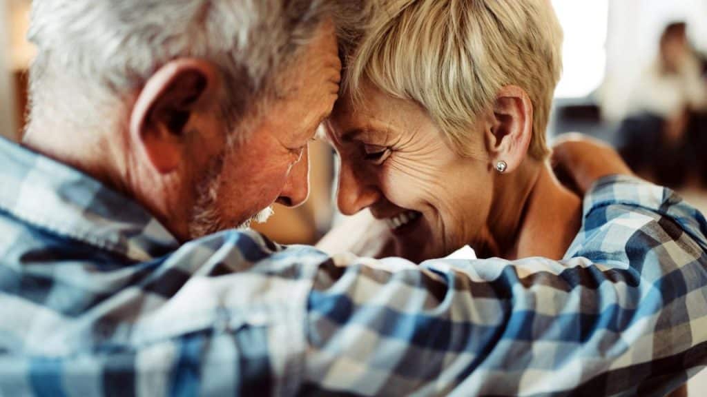 An older couple smiling closely with their foreheads touching.
