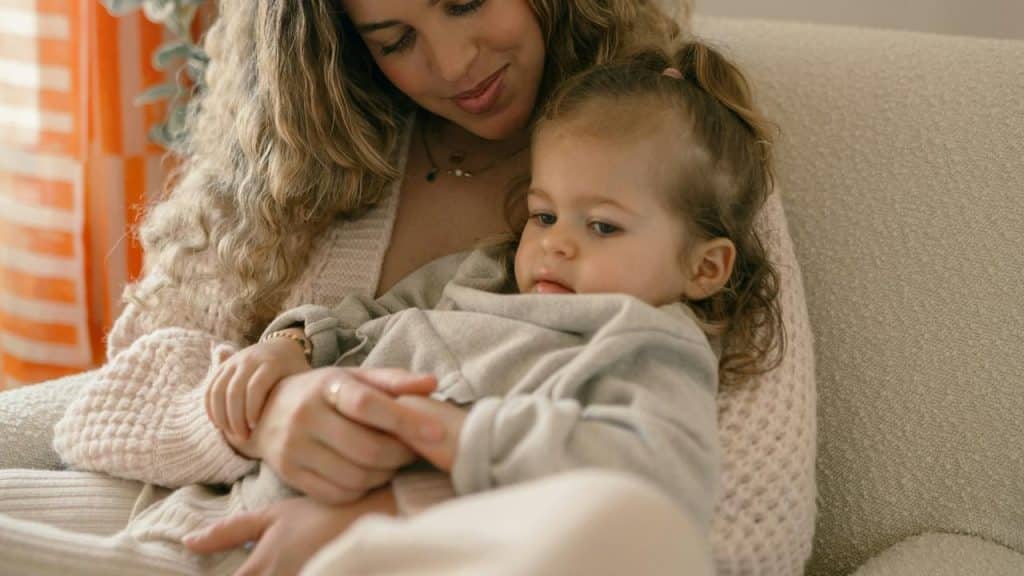 A woman cuddling a small child on a cozy chair.