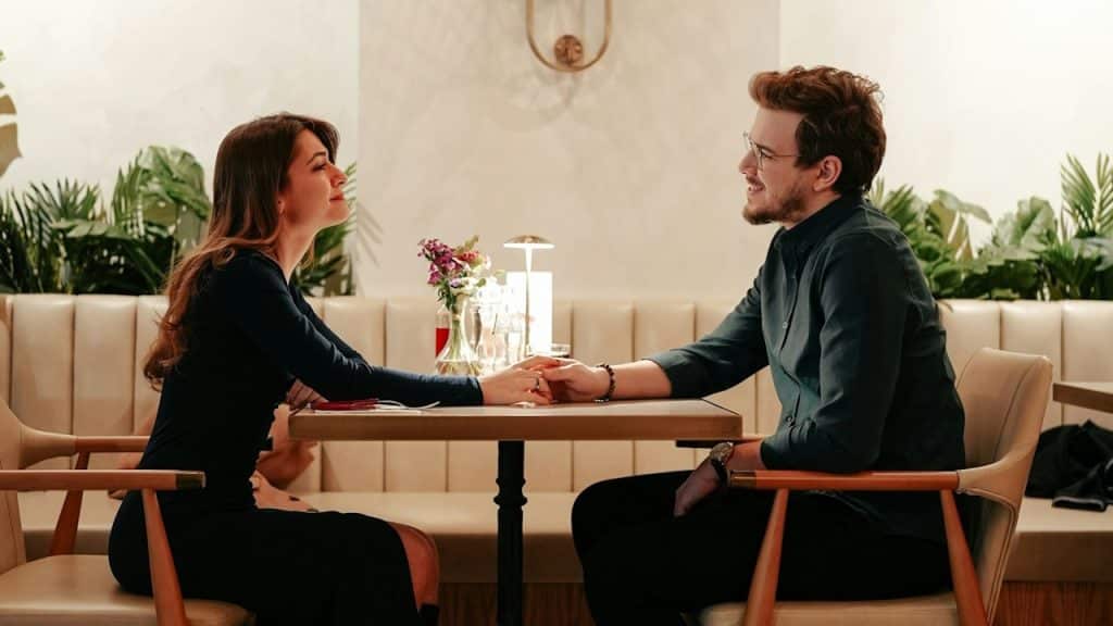 A couple sitting at a table and holding hands.