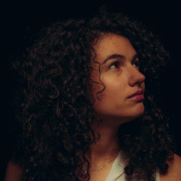 A woman with curly hair looking upwards.