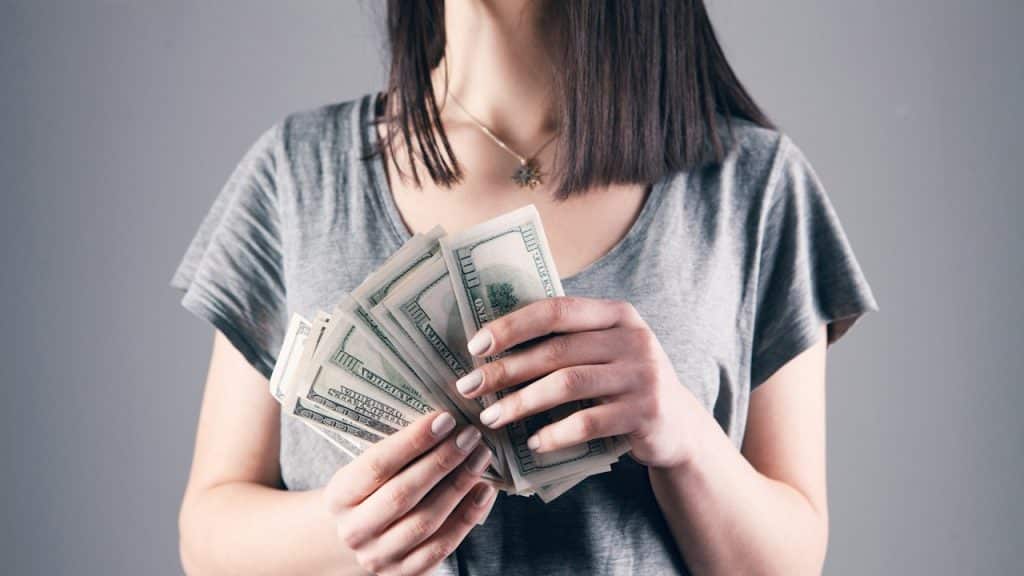 A woman holding 100 dollar bills in her hands.