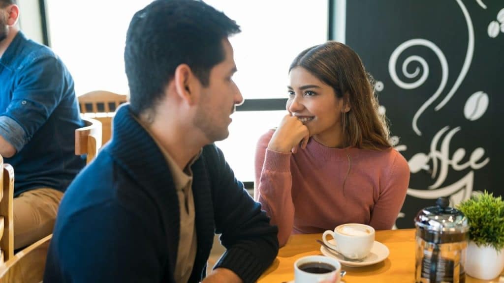 Man and woman having coffee, sitting and looking at each other in a café.