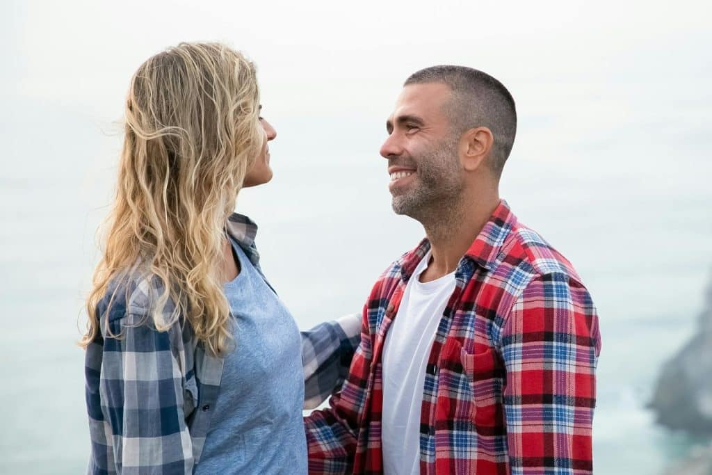A couple standing face to face and smiling.