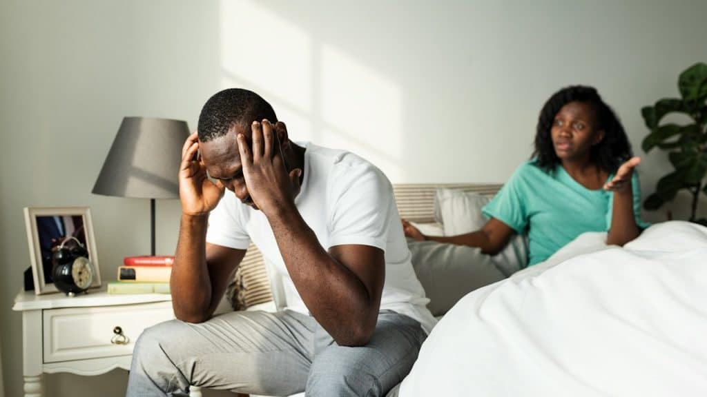 A couple having an argument while they are sitting on a bed.
