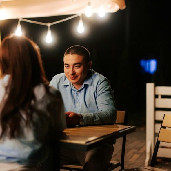 A man looking at the woman sitting across from him.
