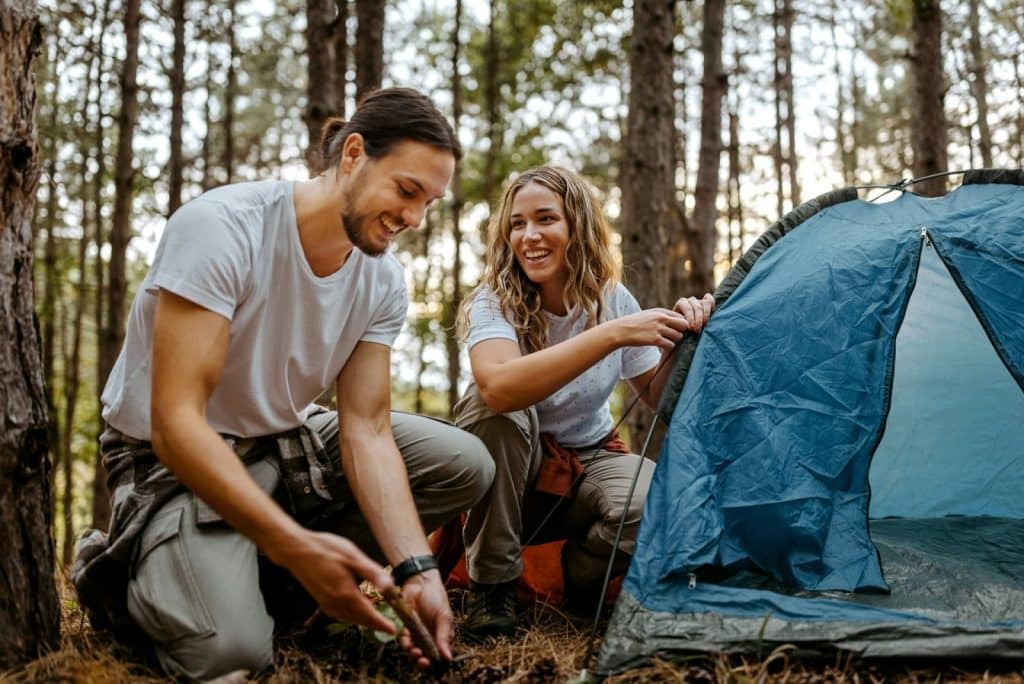 A couple setting up a tent in the forest.